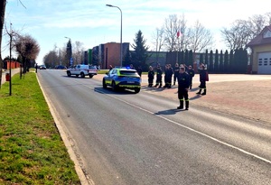 Strażacy obok radiowozu policyjnego, dalej radiowóz strażacki.