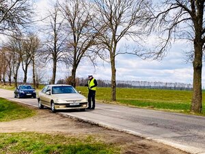 Samochody na drodze i policjant dokonujący kontroli drogowej.