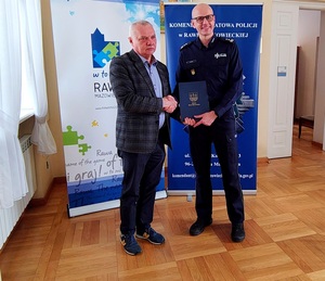 Komendant i zastępca Burmistrza stoją na tle rolapów i gratulują sobie.