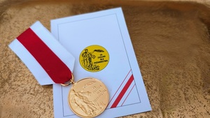 Zloty medal leżący obok legitymacji