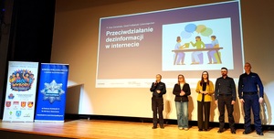 Policjanci, przedstawiciele NASK na scenie i ścianki z napisem Policja i Moc Wyboru.