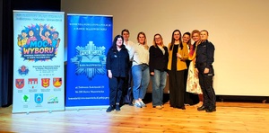 Policjanci przedstawiciele NASK oraz nauczyciele z jednej ze szkół na scenie.