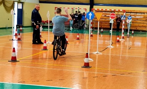 Dziecko jadące na rowerze na torze przeszkód i policjant.