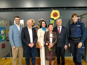 Policjantka oraz inne osoby na zdjęciu stojące obok siebie.