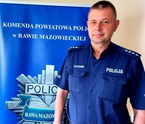 Policjant na tle rolapa z napisem gwiazda policyjna z napisem Rawa Mazowiecka.