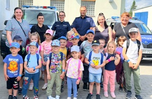 Policjanci, nauczycielki i dzieci na tle radiowozów.