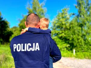 Policjant trzymający dziecko na rękach.