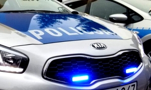 Radiowóz z włączonymi sygnałami świetlnymi z pokrywie silnika.