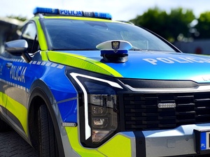 Radiowóz policyjny i czapka policjanta ruchu drogowego na masce.