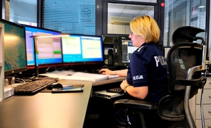 Policjantka siedząca przy monitorach na dyżurce.