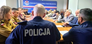 Policjanci, dyrektorzy szkół i urzędnicy siedzący przy jednym stole.