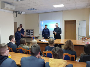 młodzież ze szkoły wraz z księdzem i policjantami w komendzie