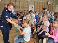 Policjantka rozdaje dzieciom odblaski.